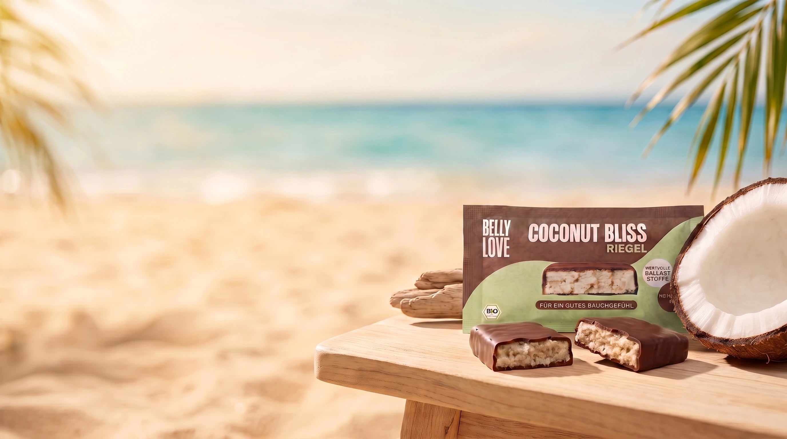 Coconut Bliss Bio Riegel am Strand mit offener Kokos unter Palmen und zwei angebissenen Produkten