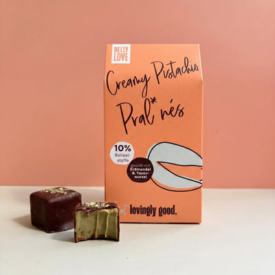 Creamy Pistachio Pralinés von Belly Love – Verpackung mit Pralinés, eine angebissen